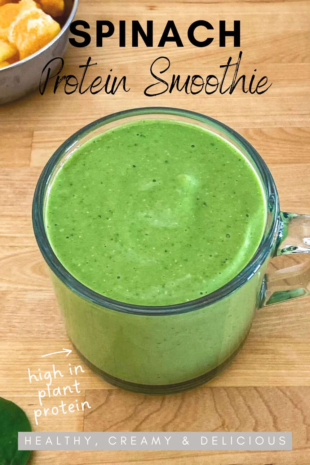 Spinach protein smoothie in a glass cup on wooden counter with black and white tea towel, text overlay reads ‘Spinach Protein Smoothie – Healthy, Creamy & Delicious’
