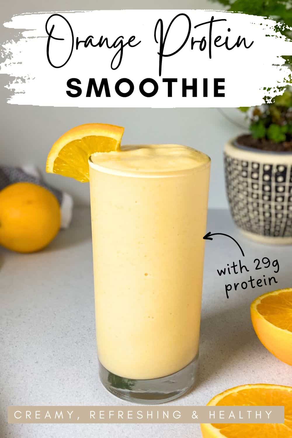 Tall glass of and orange smoothie with a thick creamy texture, garnished with a fresh orange slice on the rim, text overlay highlighting 29g protein and tagline creamy refreshing and healthy