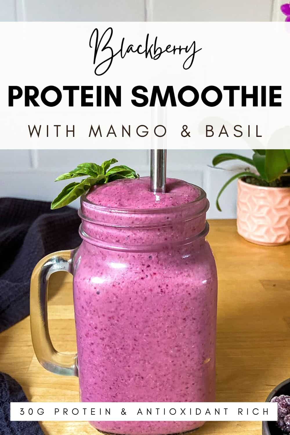 A vibrant blackberry and mango smoothie in a glass jar topped with fresh basil, with a metal straw and warm wooden background. The text overlay reads “Blackberry Protein Smoothie with Mango & Basil – 30g Protein & Antioxidant Rich.”