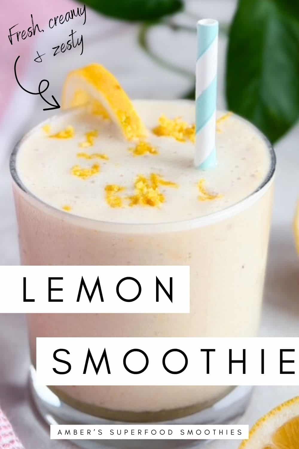 A creamy lemon smoothie in a clear glass topped with fresh lemon zest and a lemon slice, with a striped blue straw, sliced lemons, and a pink tea towel beside it on a light background, with the words “Lemon Smoothie” and “Fresh, creamy and zesty” overlaid on the image