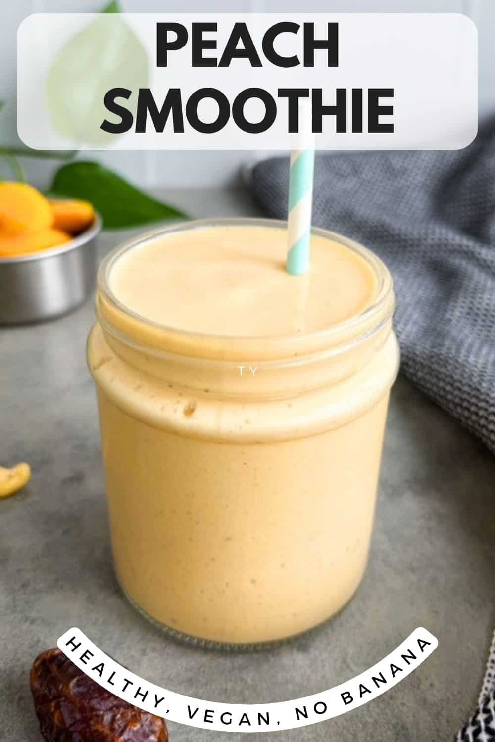 Peach smoothie in a glass jar with a straw on a grey surface, with peach slices, cashews, and a date in the background and text overlay reading “Peach Smoothie” and “Healthy, Vegan, No Banana.”