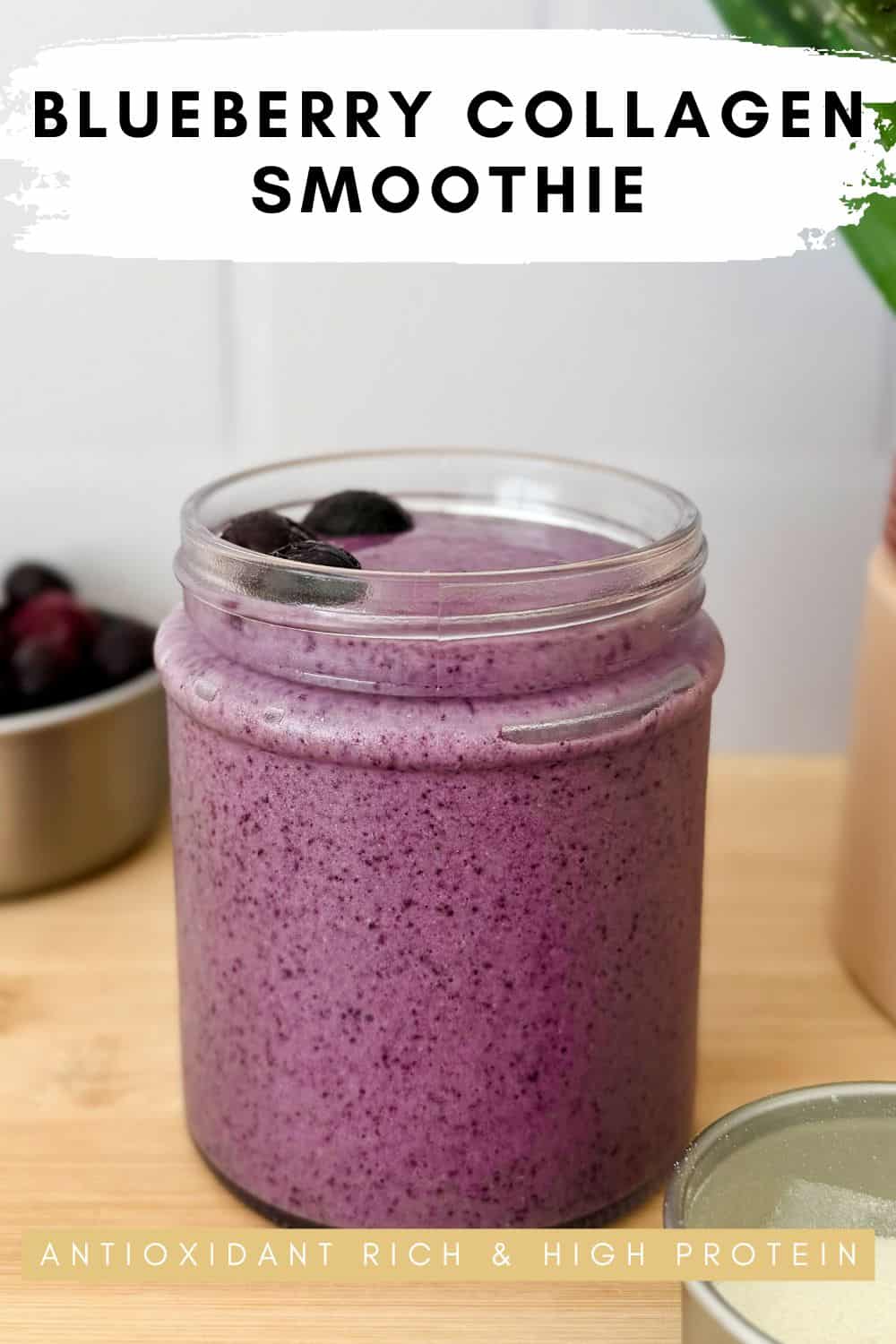 Purple blueberry collagen smoothie in a clear glass cup topped with frozen blueberries.